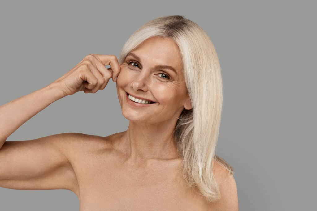 Skin Tightening Concept. Happy Beautiful Mature Woman Touching Her Cheek